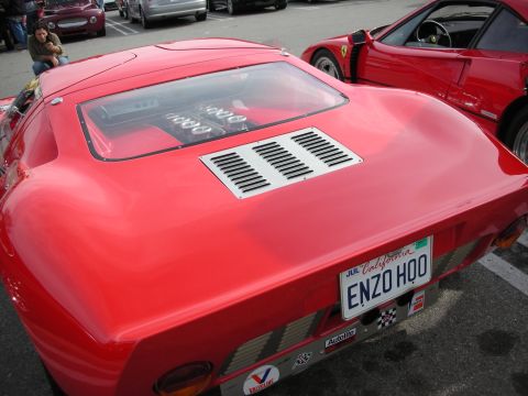 1998 Ford Crown Victoria - Overhead rear view of a red GT40-style coupe with a louvered engine deck and ENZO HQO plate, parked next to a red Ferrari.