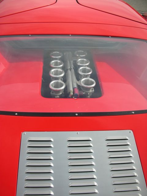1998 Ford Crown Victoria - Looking down on a red sports car's rear deck, a clear cover reveals eight polished velocity-stack intake trumpets above a louvered silver p…