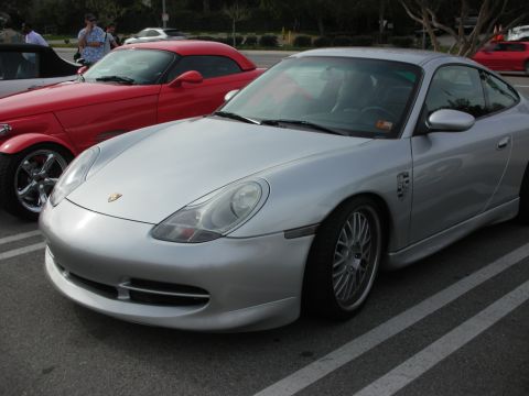 1998 Ford Crown Victoria - silver Porsche 911 coupe on multi-spoke wheels sits in a parking lot beside a red roadster at a car gathering.