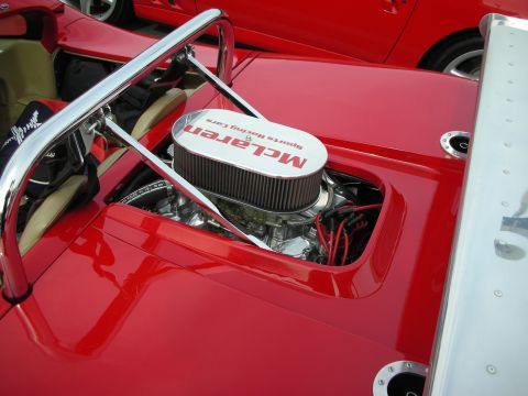 1998 Ford Crown Victoria - engine bay of a red sports-racing car shows a chrome air cleaner lettered 'McLaren Sports Racing Cars' beneath a roll hoop.
