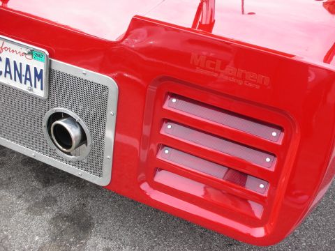 1998 Ford Crown Victoria - Rear corner of a red race car showing red louvered vents, a chrome exhaust outlet, California plate and 'McLaren Sports Racing Cars' script.