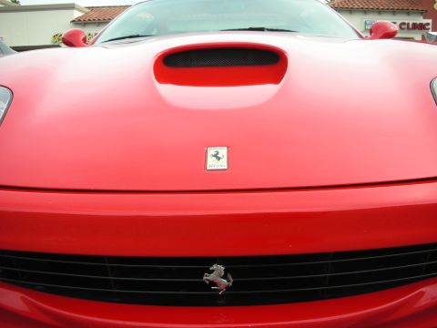 1998 Ford Crown Victoria - Close front view of a red Ferrari showing the rectangular Ferrari shield badge, prancing-horse grille emblem and central hood vent.