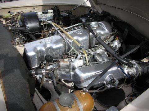 1998 Ford Crown Victoria - engine bay of a vintage Mercedes-Benz showing a polished inline engine with the Mercedes star stamped on the valve cover.