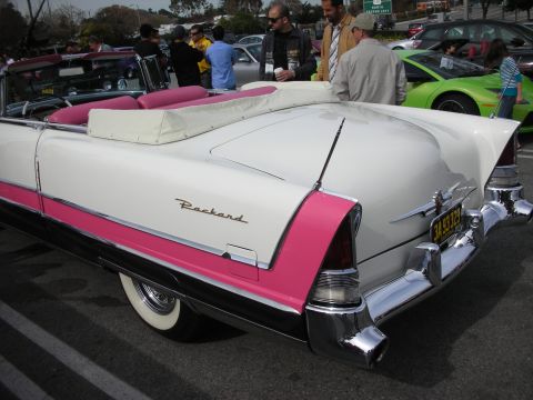 1998 Ford Crown Victoria - Rear three-quarter view of a white-and-pink 1950s Packard convertible with whitewall tires and chrome bumpers at a show.