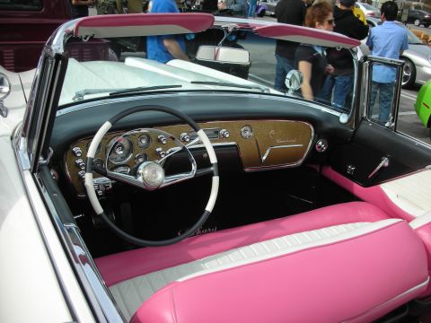 1998 Ford Crown Victoria - Interior of a pink-and-white 1950s Packard convertible showing a chrome dash, gold trim, and a white steering wheel.
