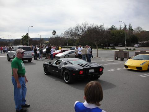1998 Ford Crown Victoria - black Ford GT with twin racing stripes and a yellow Lamborghini Gallardo draw a crowd at an outdoor car meet.