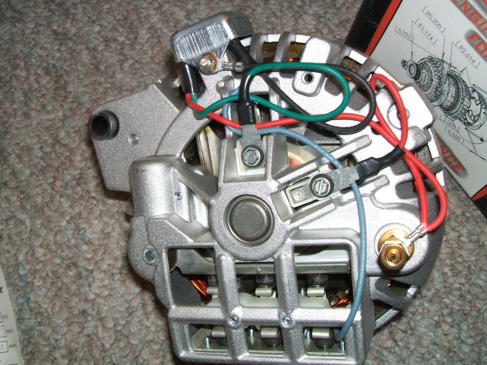 Rebuilt alternator rear housing with rectifier, output stud and colored leads on carpet