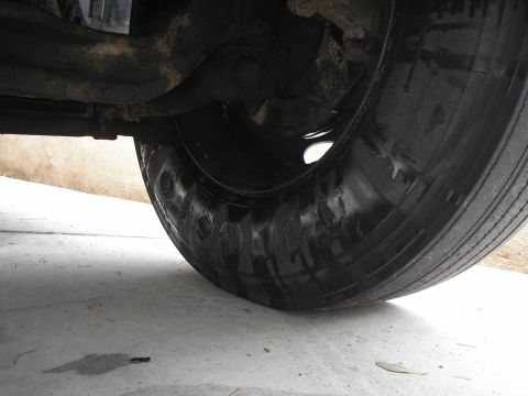 1999 Ford F-800 - A flat truck tire is visible, along with suspension components and a concrete surface.