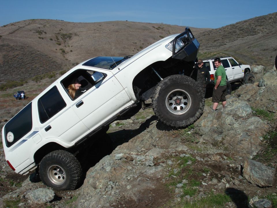 White Toyota 4Runner climbing rocks, another white SUV behind it