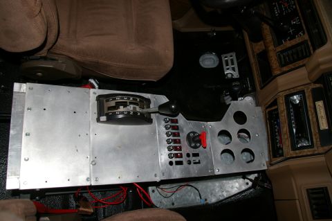 1986 Ford Bronco - A custom fabricated bare-aluminum center console fitted between tan cloth bucket seats, carrying a ratchet-style automatic shifter with 1-2…
