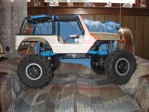 1984 Ford Bronco - This remote-controlled Jeep features a roll cage and oversized tires, displayed on a patterned surface.