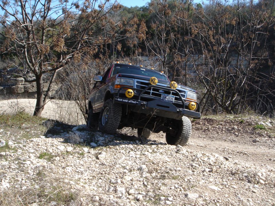 Ford F-series truck on a rocky trail, has KC lights and smiley face decals