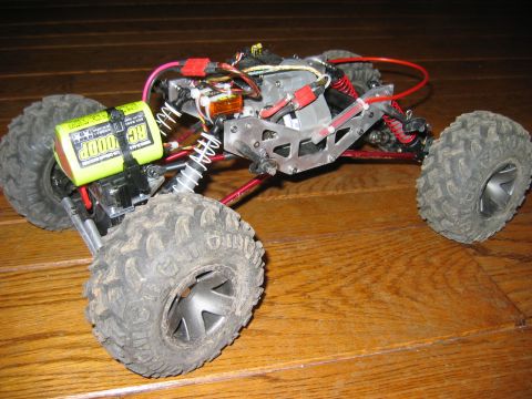 1985 Ford Bronco - This remote-controlled rock crawler sits on a wooden surface, its suspension and wiring.