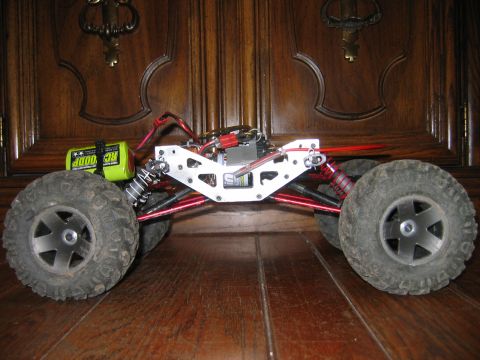 1985 Ford Bronco - Side view of a custom-built RC rock crawler chassis with a prominent battery and suspension system.