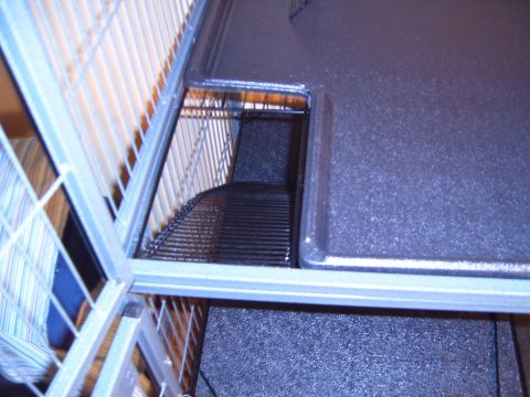 1993 Ford Bronco - Interior view of a multi-level animal cage with a dark plastic base and a wire ramp.