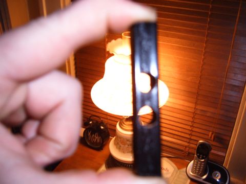 1993 Ford Bronco - Close-up of a black plastic part with holes, with a lamp and phone in the background.