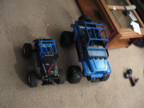 1990 Ford Bronco - Two remote-controlled trucks are on a carpeted floor next to a wooden table.