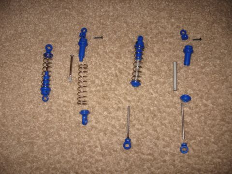 1990 Ford Bronco - Disassembled blue shock absorber components and springs are laid out on a carpeted surface.