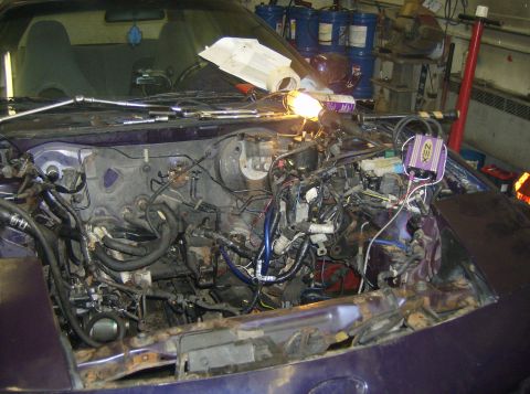 1996 Ford Probe - The engine bay of a car is shown with the engine removed, revealing numerous wires and components.