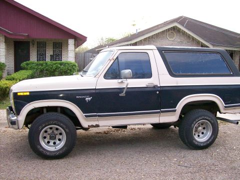 1981 Ford Bronco - A two-tone Ford Bronco is parked in front of a residential building.