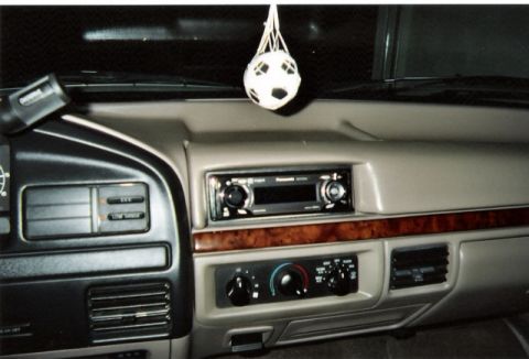 1996 Ford Bronco - Interior view of a tan dashboard with an aftermarket stereo and wood trim accents.