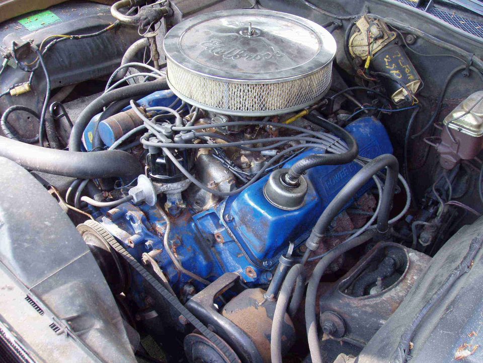 Engine bay with blue valve covers and a chrome air cleaner. Visible hoses and wiring. Some rust present