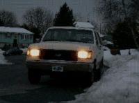 1988 Ford Bronco - A 1987 Ford Bronco is seen from the front in a snowy environment with its headlights illuminated.