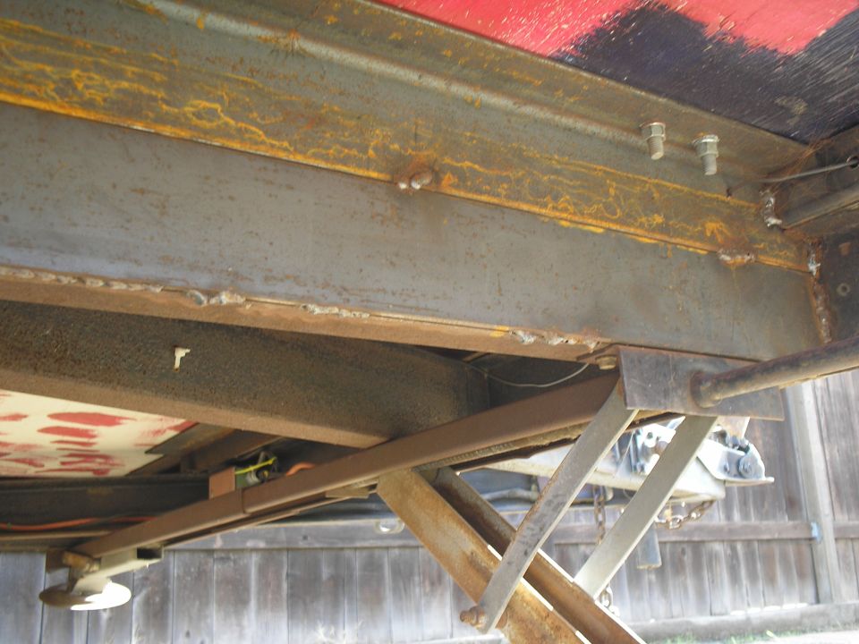 Trailer frame with rusty metal beams and a scissor jack extended