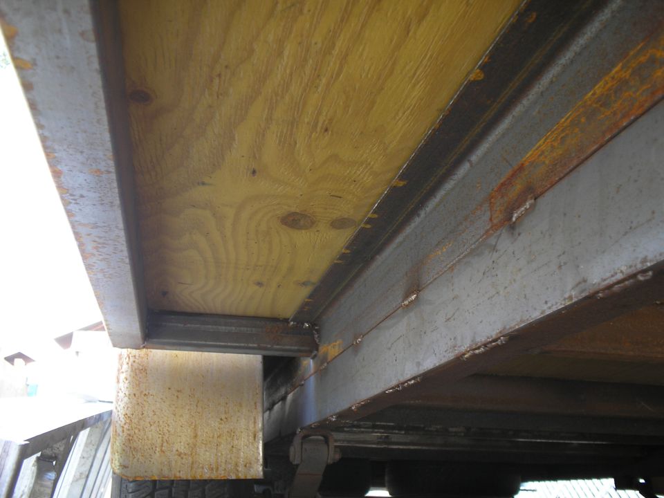 trailer bed made of wood planks over metal frame, showing rust and wear