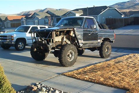 1986 Ford Bronco - This heavily modified SUV, likely from the 1980s, has had its front end stripped and features oversized off-road tires.