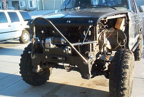1986 Ford Bronco - This 1986 Ford Bronco features a custom front bumper and winch, with a white SUV visible in the background.