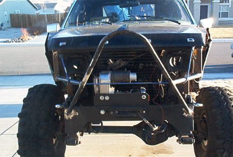 1986 Ford Bronco - Front view of a modified 1980s Ford Bronco, a custom roll cage and winch.