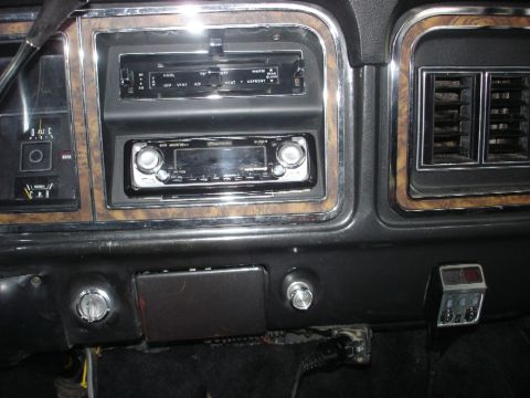 1979 Ford Bronco - The dashboard features wood grain trim around the radio and climate controls, with aftermarket audio equipment installed.