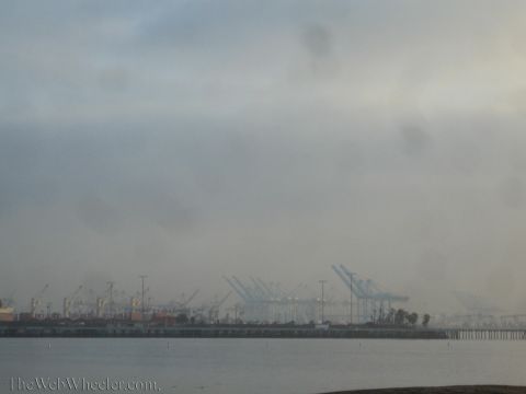1990 Ford Bronco - Foggy view across the water of an industrial port lined with rows of container gantry cranes under an overcast sky.