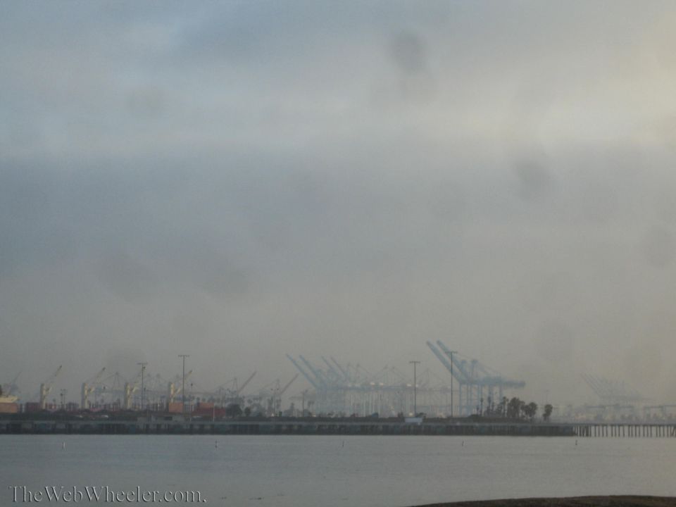 Foggy industrial port skyline with rows of container cranes across the water