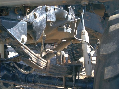 2005 Ford Excursion - Undercarriage view shows the leaf spring and shock absorber assembly of a heavy-duty truck.