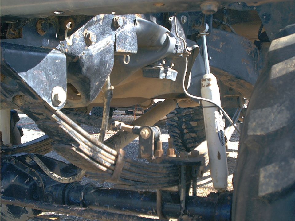 Close-up of a truck's rear leaf spring suspension and shock absorber