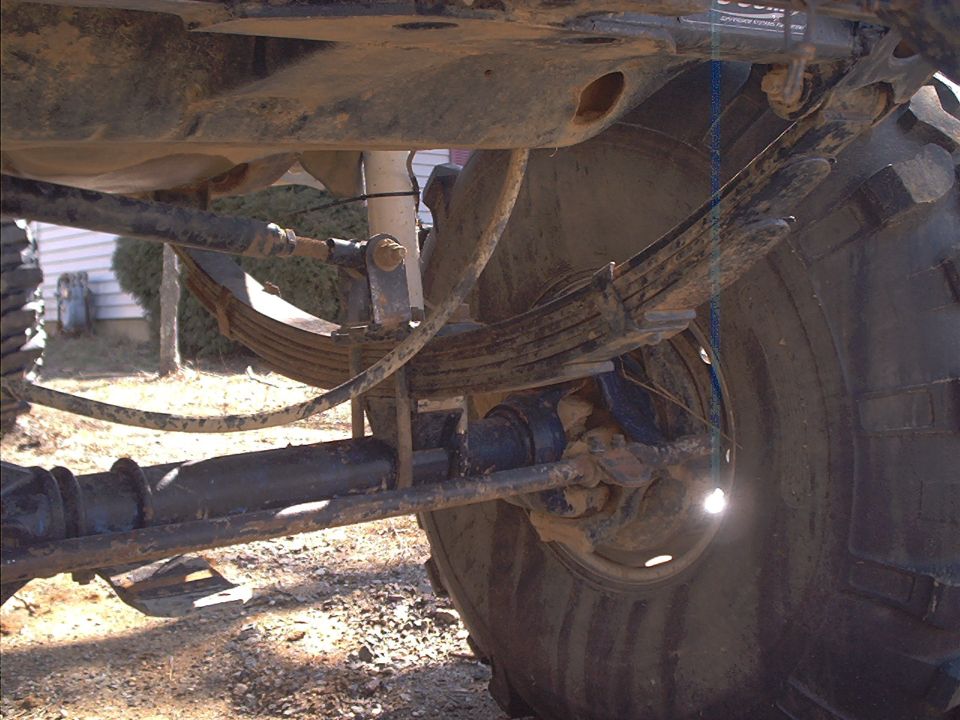 Undercarriage view of a vehicle's rear suspension with large tires and leaf springs