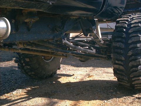 2005 Ford Excursion - The underside of a heavily modified off-road vehicle shows its robust suspension and large tires.