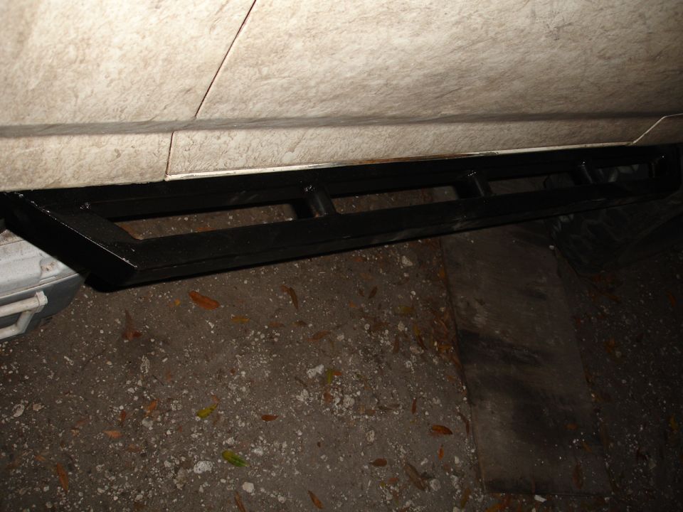 Black metal running boards attached to the side of a vehicle
