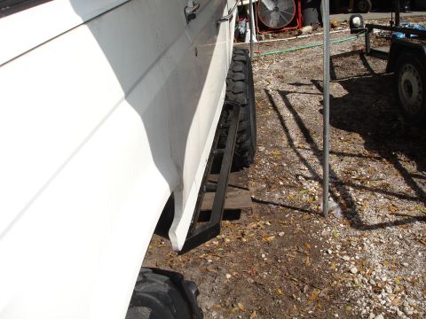 1989 Ford Bronco - Side view of a white SUV with custom running boards and off-road tires.