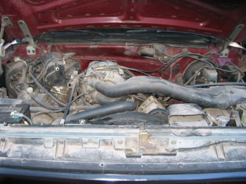 1991 Ford Bronco - The engine compartment of a vehicle, showing various mechanical parts and wiring.