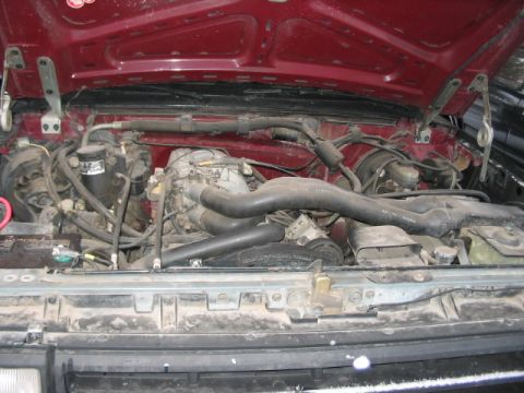 1991 Ford Bronco - The engine bay of a red 1992 Ford F-150 shows a V8 engine with various hoses and wiring.