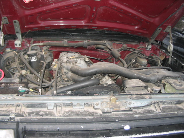 Red 1992 Ford F-150 engine bay with V8 engine, hoses, and wiring visible