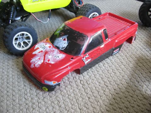 1974 Ford F-100 - RC truck body with decals sits next to a yellow RC vehicle on a carpeted surface.