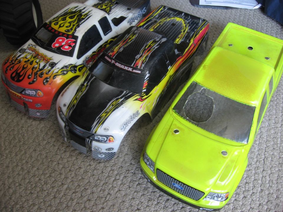 Three remote control truck bodies, two with flame graphics and one neon yellow