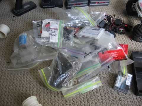 1974 Ford F-100 - Various RC car parts and accessories are organized in plastic bags on a carpeted surface.