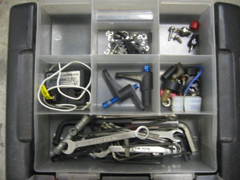 1974 Ford F-100 - A toolbox filled with various RC car parts and tools, including servos, screws, and wrenches.