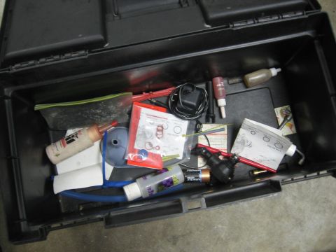 1974 Ford F-100 - Contents of a toolbox, including fluids, parts, and a power adapter.