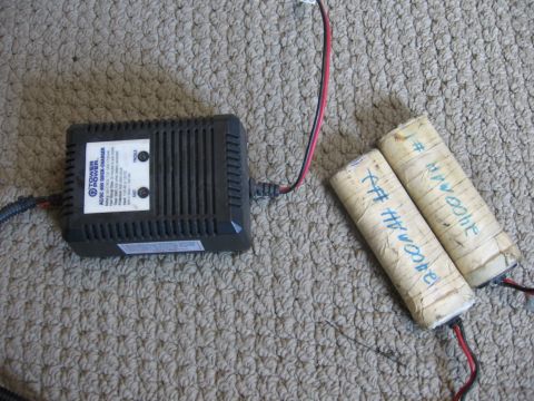 1974 Ford F-100 - A battery charger and two cylindrical batteries are placed on a carpeted surface.